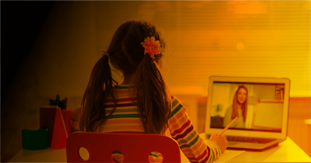 Foto zum Thema "Neuanfang in der Bildung?", was ein Mädchen vor dem Laptop zeigt, auf dem eine Lehrerin vor dem Whiteboard steht.